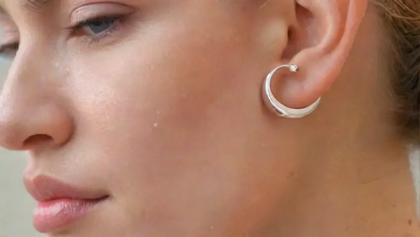 Un pendiente en espiral con brillo suave y delicados reflejos presenta una atmósfera serena y cuidada